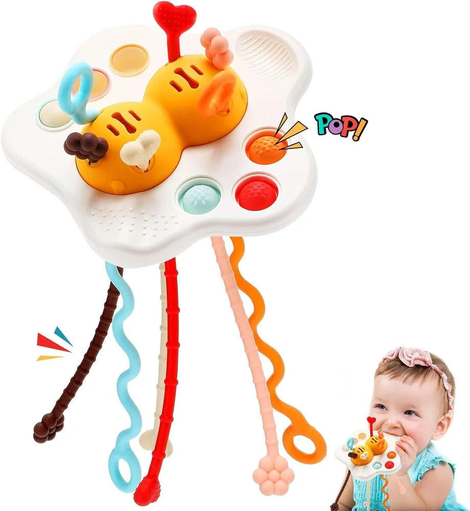 A colorful baby sensory toy with a white cloud-shaped base, two orange caterpillar-like figures, and multiple dangling wavy sensory bars in blue, red, brown, pink, and orange. A baby is shown holding the toy in the lower right corner against a plain white background.